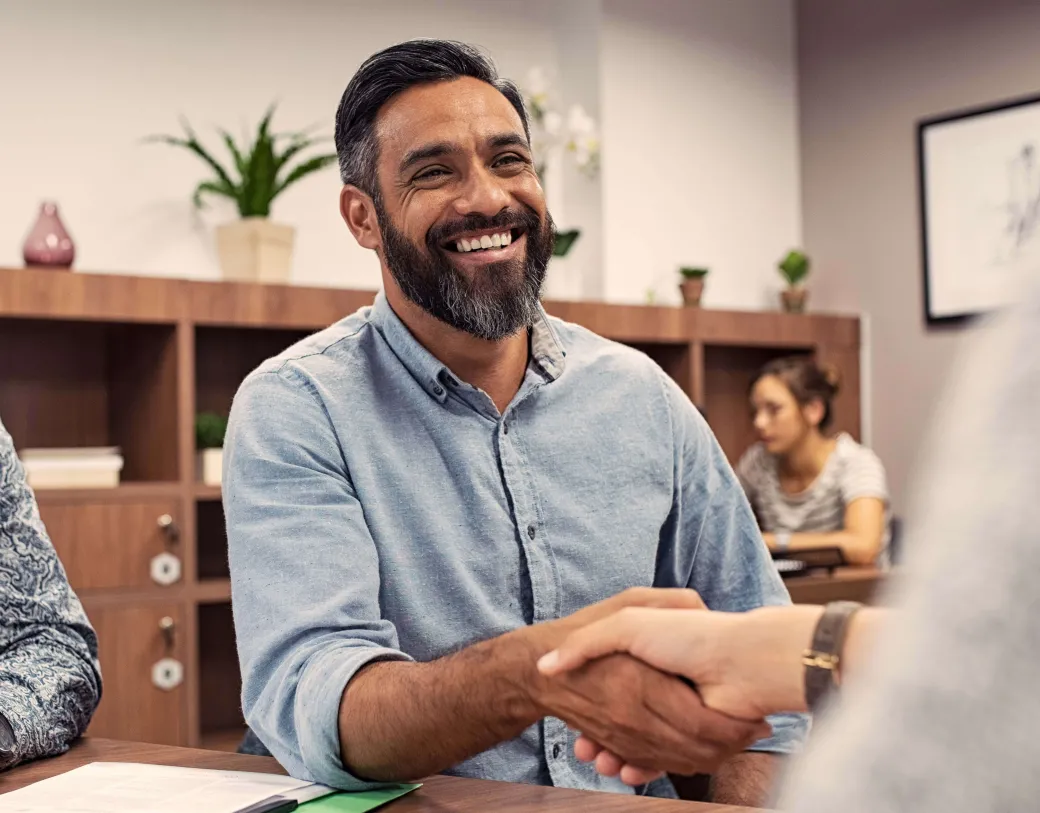 Two people shaking hands in an office.