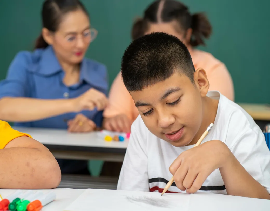 Boy drawing a picture in a classroom.