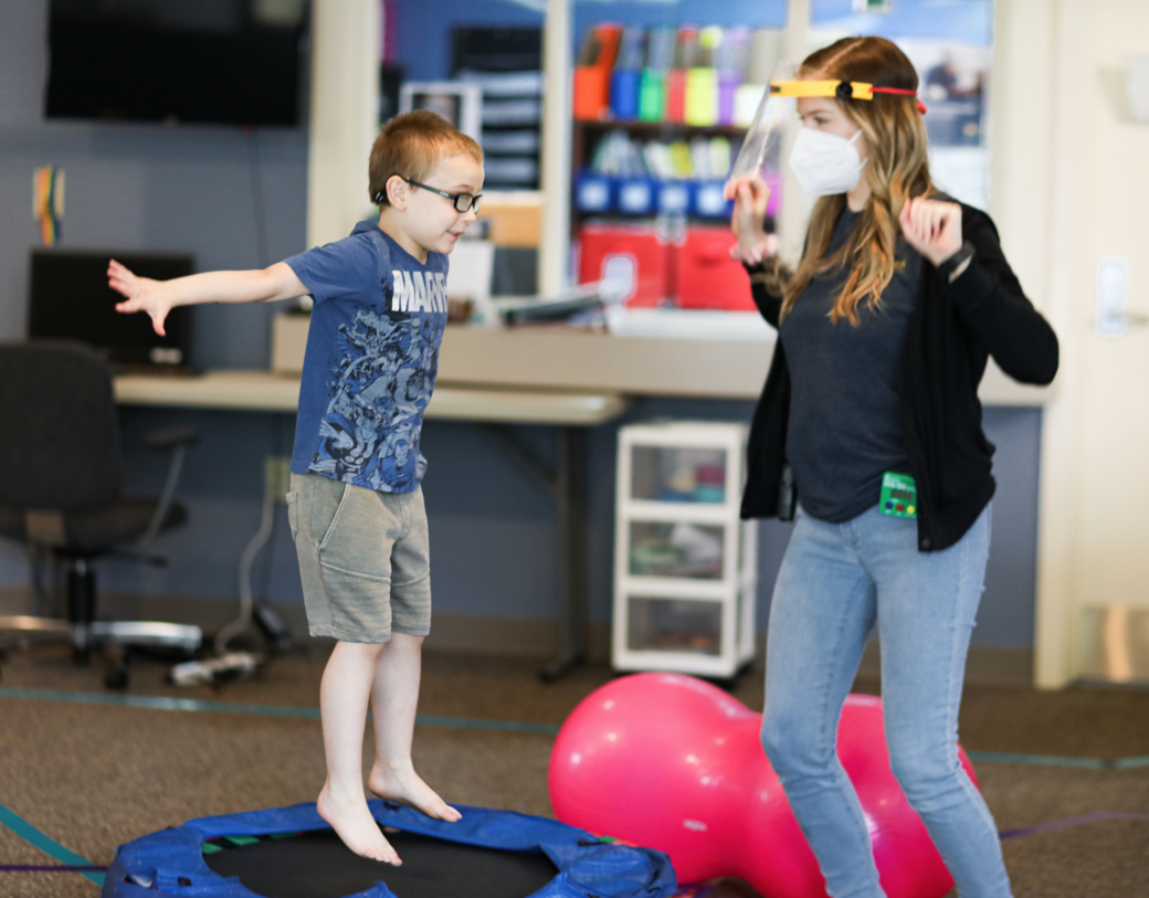 Child excitedly jumping with staff member.