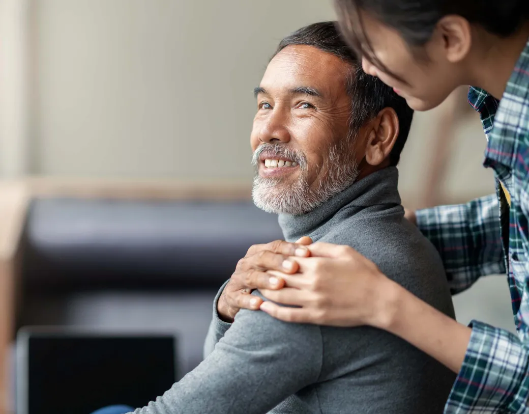 Woman supporting adult sitting man in chair.