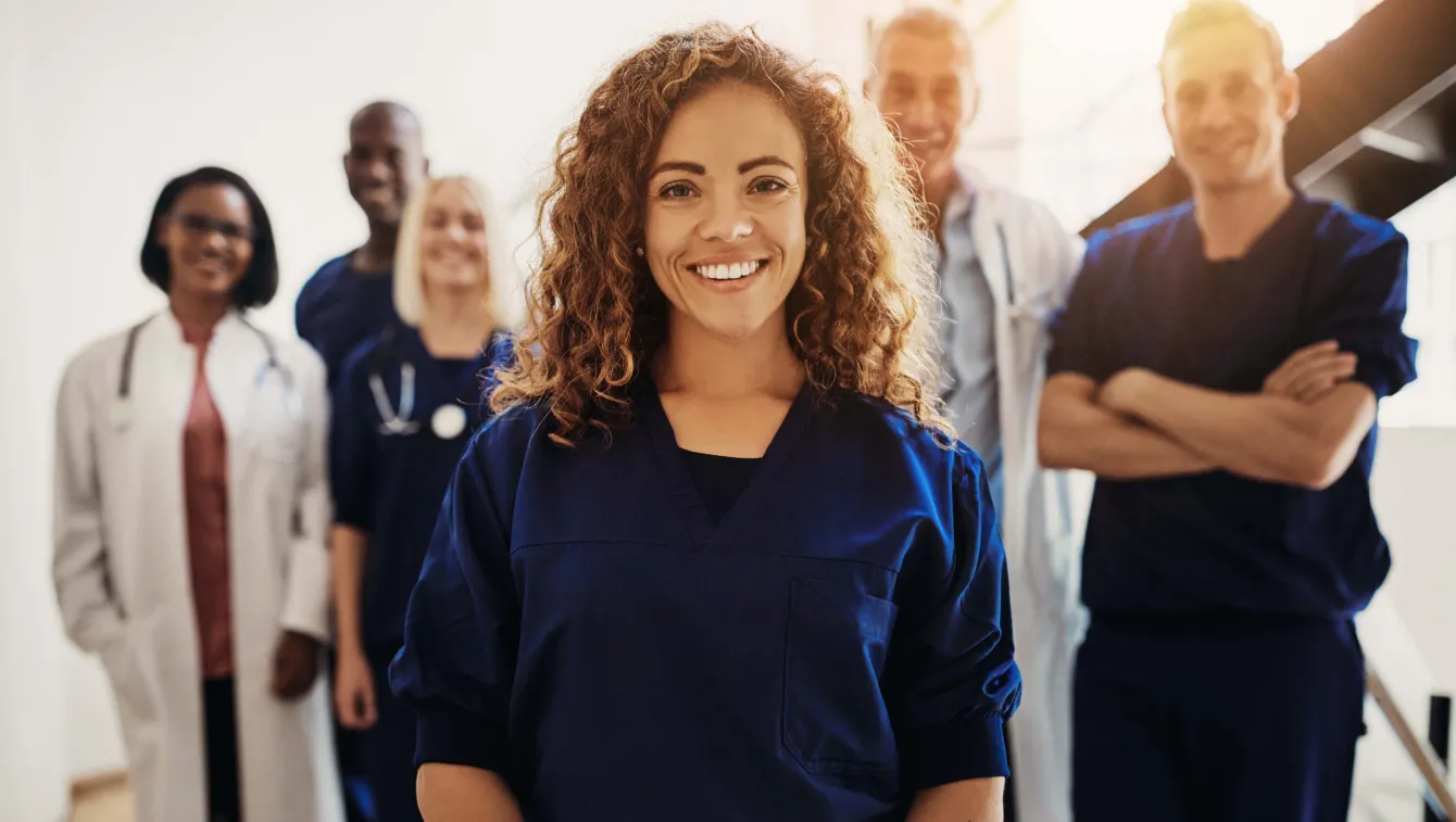 Smiling doctor standing with medical colleagues in a hospital.