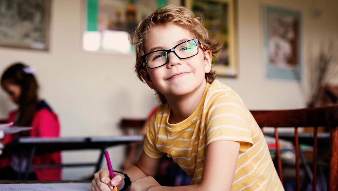 Child sitting at desk in school classroom.